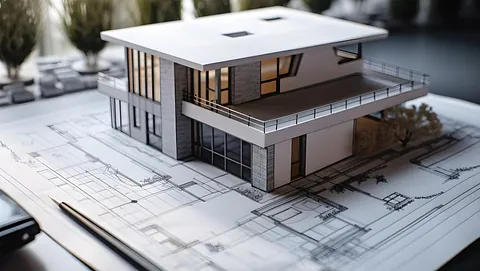 Arkitektmodell av moderne enebolig plassert på byggetegninger med detaljerte plantegninger.